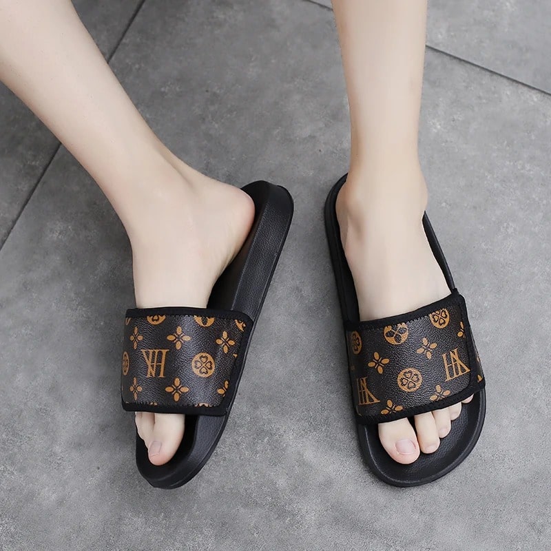 Man wearing VilyVital black leather slides with brown print pattern on grey tile floor